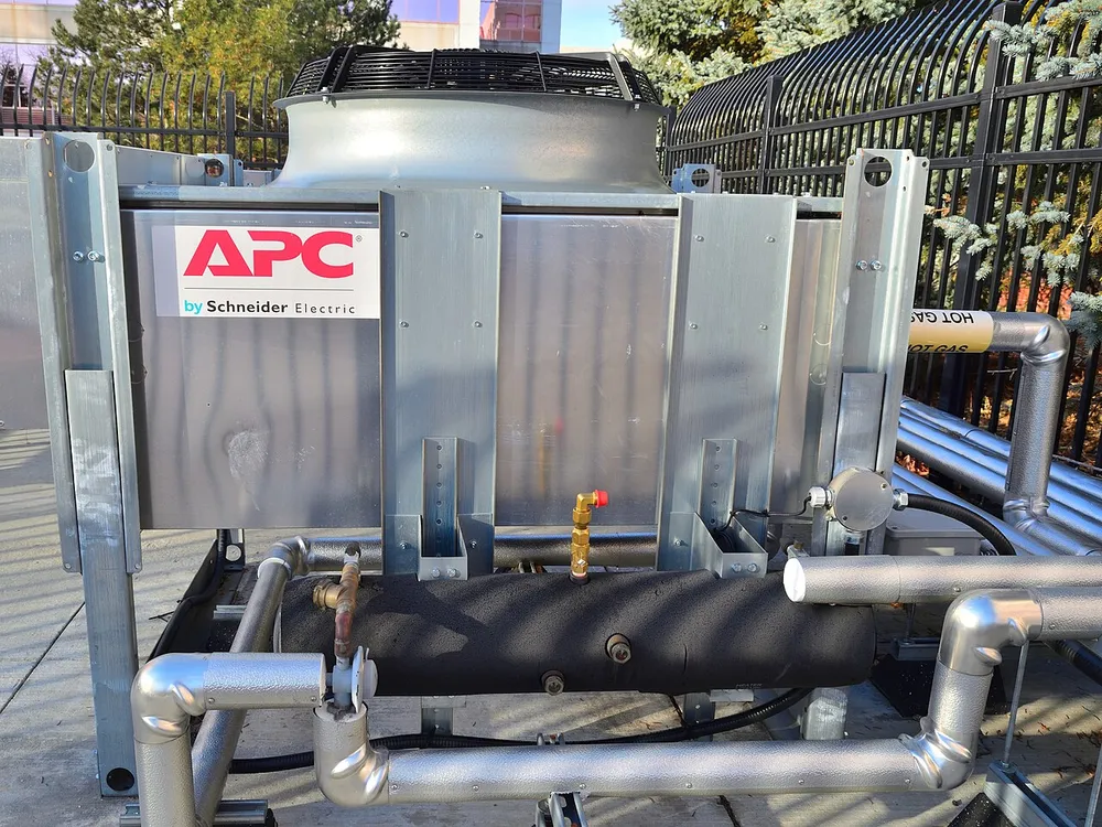 Outdoor data-center cooling equipment with pipes and a fan.