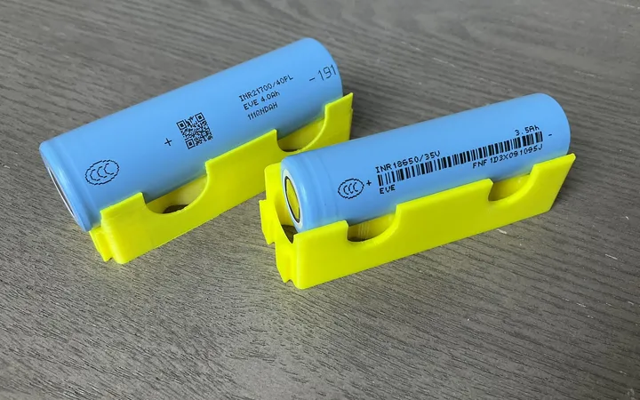 Two blue cylindrical lithium-ion cells resting in yellow holders.