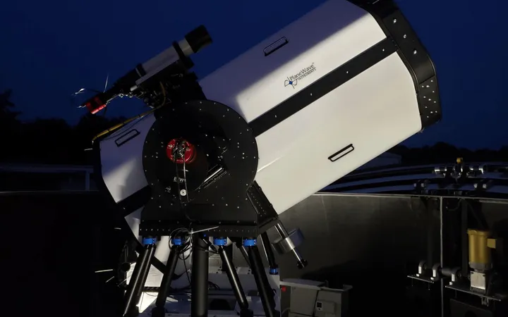 The large white telescope and tracking mount of NASA’s Low-Cost Optical Terminal under a dark blue sky.